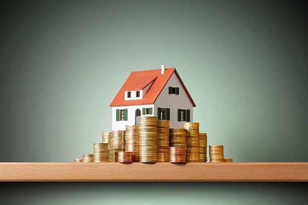 House on money stack Miniature model house standing on a stack of coins. How to finance a real estate purchase stock pictures, royalty-free photos & images